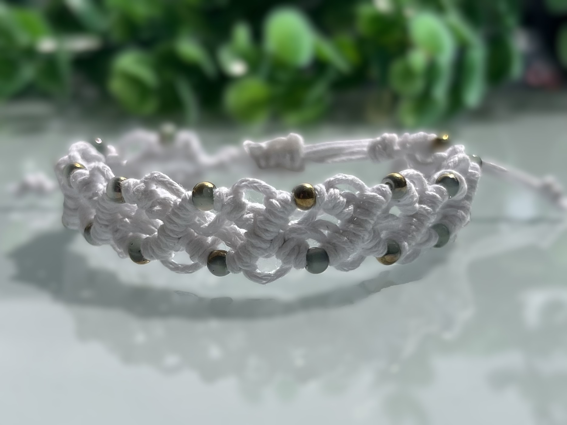 White macrame bracelet with soft gold and green accents